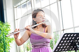 Flute classical instrument profestional player playing song.  A young and elegant Asian woman plays the flute