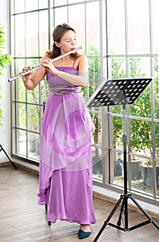 Flute classical instrument profestional player playing song.  A young and elegant Asian woman plays the flute