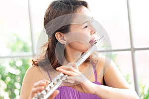 Flute classical instrument profestional player playing song.  A young and elegant Asian woman plays the flute