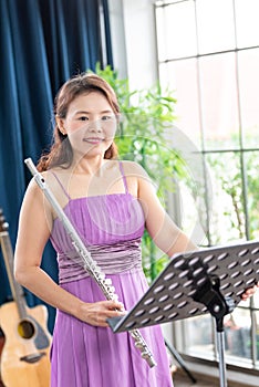 Flute classical instrument profestional player playing song.  A young and elegant Asian woman plays the flute