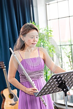 Flute classical instrument profestional player playing song.  A young and elegant Asian woman plays the flute