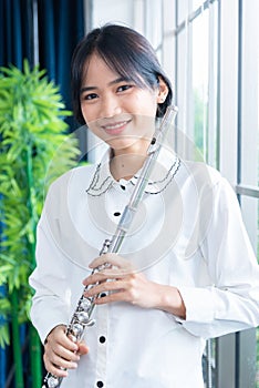 Flute classical instrument profestional player playing song. A young and elegant Asian woman plays the flute