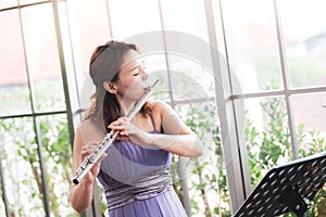 Flute classical instrument profestional player playing song.  A young and elegant Asian woman plays the flute. Vintage Stye