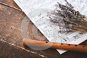 Flute with notes and lavender on the wooden table