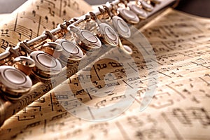 Flute and old sheet music on black table front elevated view