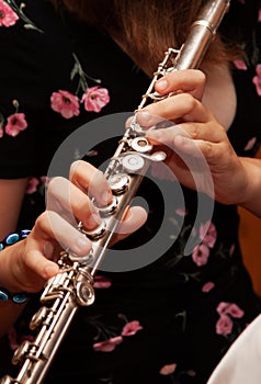 Flutist, young girl playing the flute, hands, fingers on keys closeup, children playing transverse side blow flute, detail shot