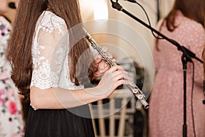 Flutist, young girl playing the flute, hands, fingers on keys closeup, children playing transverse side blow flute, detail shot,