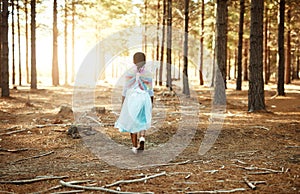 Fluttering through the forest. Rear view shot of a little girl walking in the woods while dressed up as a fairy.