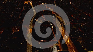 Fly above block of buildings between two illuminated streets. Aerial view of urban district at night. Barcelona, Spain