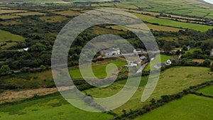 Fly above meadows and pastures in countryside. Tilt up reveal panoramic view with hills in background. Ireland