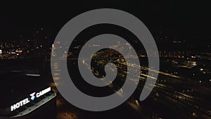 Fly above night city. Aerial view of illuminated platforms on train station, train approaching platform. Copenhagen