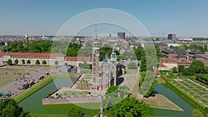 Fly above town park. Slide and pan shot of historic Rosenborg castle surrounded by water fortification. Copenhagen