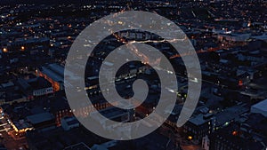 Fly above urban neighbourhood at night. Aerial view of buildings and streets lit by lights. Limerick, Ireland