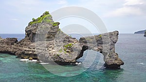 Fly Around Beautiful Rock Arch Island in the Sea at Atuh Beach in Nusa Penida, Indonesia. 4K Aerial.