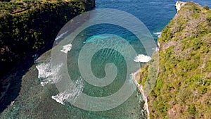 Fly around cliff and rocks over ocean along coast