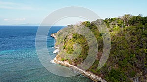 Fly around cliff and rocks over ocean along coast