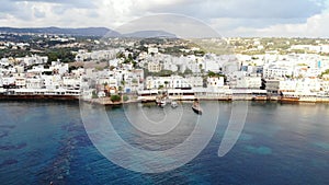 Fly away from Hersonissos, aerial view on blue sea, boats and town houses