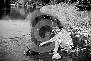 Fly fish hobby of man. Hipster in checkered shirt. hipster fishing with spoon-bait. big game fishing. relax on nature