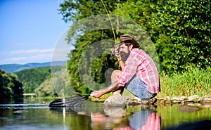 fly fish hobby. Summer activity. successful fisherman in lake water. mature bearded man with fish on rod. big game