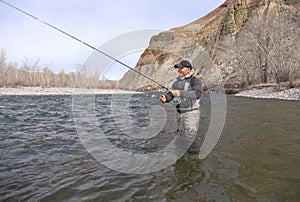 Fly fisherman casting for trout on a river