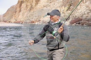 Fly fisherman casting for trout on a river close-up