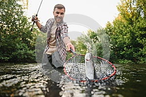 Fly-fisherman holding trout out of the water
