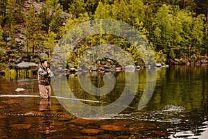 Fly fishing fisherman caught salmon fish, splashing water