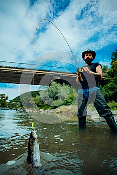 Fly fishing - method for catching trout. Fishing in river. Catches a fish. Catching a big fish with a fishing pole.