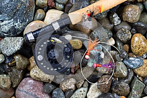 Fly Fishing Pole and Reel with Flies on Wet Stones