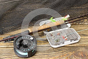 Fly fishing rod ,flie and a landing net on the old wooden table. All ready for fishing.