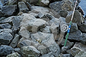 Fly fishing rod and reel on stone river bank. Fishing scene on the banks