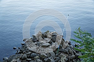 Fly fishing rod and reel on stone river bank. Fishing scene on the banks