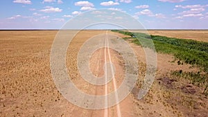 Fly over an empty dusty road via drone in desert or semi-desert region