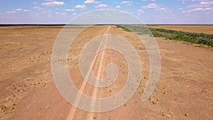 Fly over an empty dusty road via drone in desert or semi-desert region