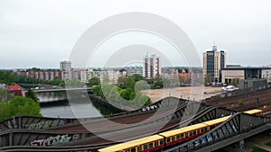 Fly over steel bridge over river in city. Suburban train running on multitrack railway line. Residential neighbourhood