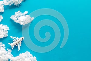 Fly by plane concept. Airplane model and clouds on blue background top view frame copy space