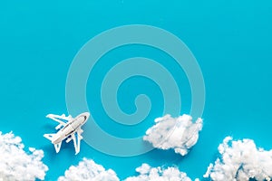 Fly by plane concept. Airplane model and clouds on blue background top view frame copy space