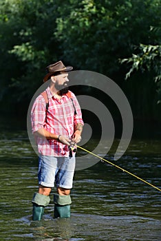 Fly rod and reel with a brown trout from a stream. Catch fish. Bearded retro fisherman and trophy trout. Men fishing in