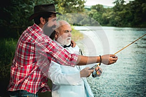 Fly rod and reel with a brown trout from a stream. Father and son relaxing together. Men fishing in river during summer