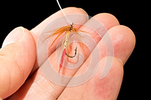 Fly to catch fish in a hand on a black background