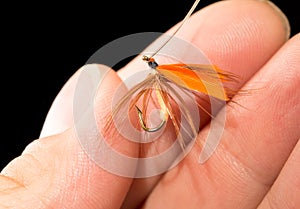 Fly to catch fish in a hand on a black background