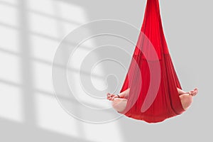 Fly yoga. A girl sits in a lotus position in a red hammock for aerial yoga doing mudras. Relaxation in yoga classes. Copy space