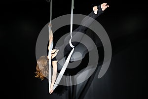 Fly yoga. Girl in a white hammock on a black background shows aerial acrobatics. Gymnastics, circus, under dome. Play of light and