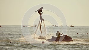 Flyboard.The silhouette of a man at sea flyboard. Sunset on the sea holidays
