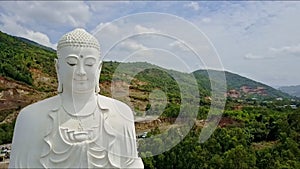 Flycam Approaches Closely to Buddha Statue Head against Hill