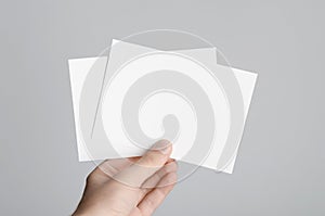 A6 Flyer / Postcard / Invitation Mock-Up - Male hands holding blank flyers on a gray background