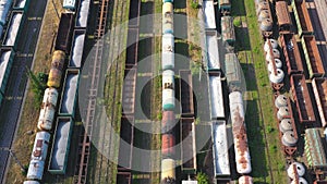 Flying above cargo trains and freight containers at industrial railroad station. Aerial shot of railroad and export