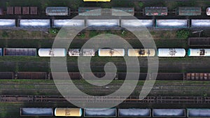 Flying above cargo trains and freight containers at industrial railroad station. Aerial shot of railroad and export