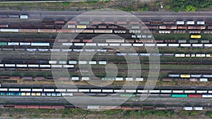 Flying above cargo trains and freight containers at industrial railroad station. Aerial shot of railroad and export