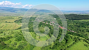 Flying above countryside spring meadows and a small village. Aerial view, Transylvania, Romania